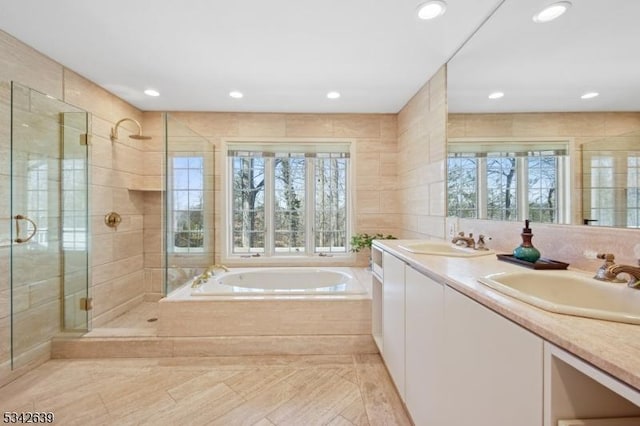 full bathroom with a sink, a garden tub, tile walls, and a shower stall