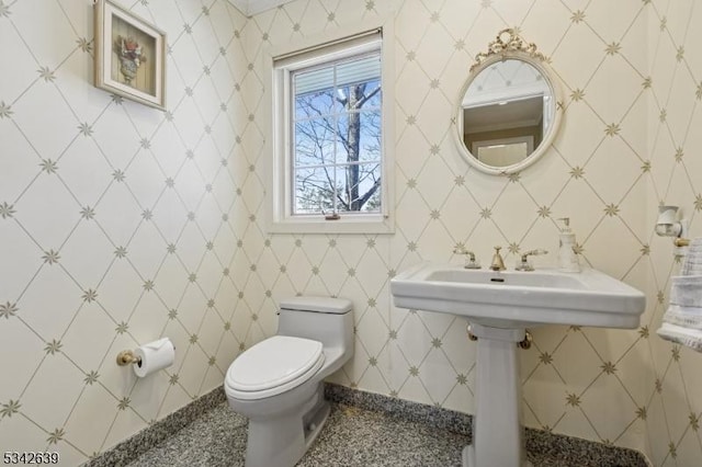 half bathroom with wallpapered walls and toilet