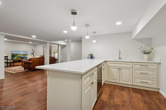 kitchen with dark wood finished floors, open floor plan, decorative light fixtures, light countertops, and a sink