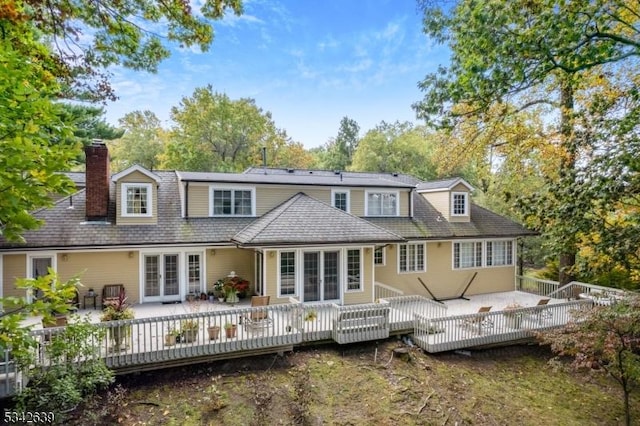 rear view of house featuring a deck, french doors, and a chimney