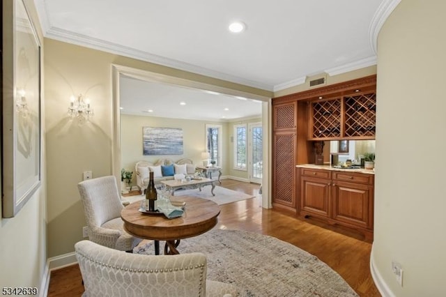 bar featuring visible vents, crown molding, baseboards, and wood finished floors