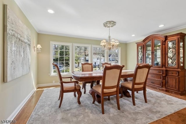 dining room with an inviting chandelier, wood finished floors, baseboards, and ornamental molding