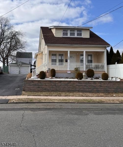 bungalow-style home with a porch, an outdoor structure, a detached garage, and fence