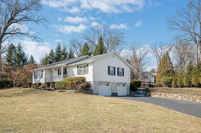 view of front of home with a garage, covered porch, driveway, and a front lawn