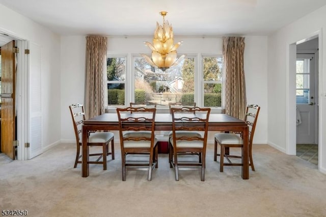 dining area featuring a healthy amount of sunlight, light carpet, and an inviting chandelier