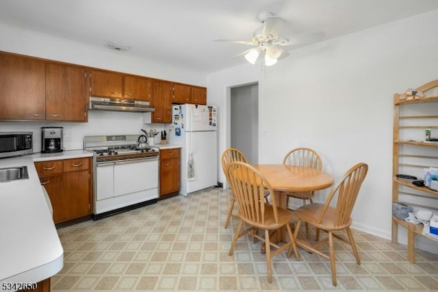 kitchen featuring light countertops, white appliances, light floors, and under cabinet range hood