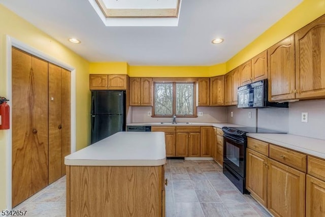 kitchen with a skylight, a sink, light countertops, a center island, and black appliances