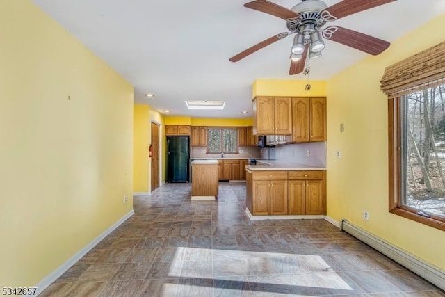 kitchen featuring baseboards, brown cabinetry, freestanding refrigerator, light countertops, and a baseboard heating unit