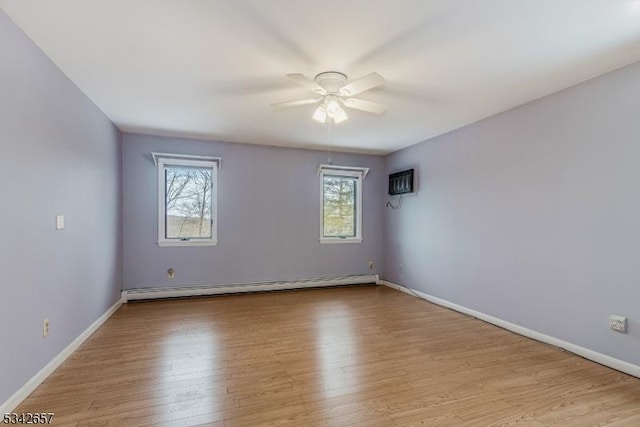 unfurnished room featuring a baseboard radiator, baseboards, and wood finished floors