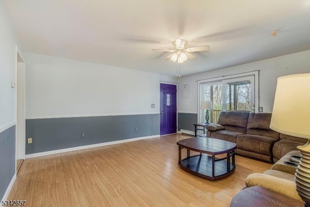 living room with ceiling fan, baseboards, and wood finished floors