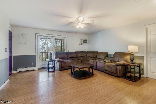 living area featuring ceiling fan, a baseboard radiator, a wall unit AC, baseboards, and light wood-type flooring