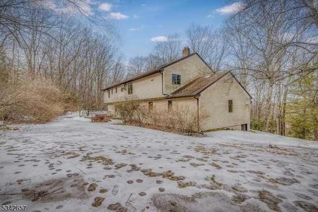 view of snow covered exterior with a chimney