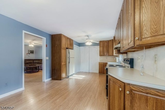 kitchen featuring brown cabinets, light countertops, electric range oven, light wood-style floors, and freestanding refrigerator