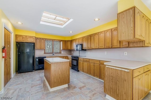 kitchen featuring a skylight, a sink, light countertops, a center island, and black appliances