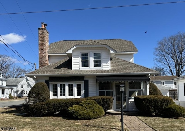 view of front facade with a chimney and roof with shingles