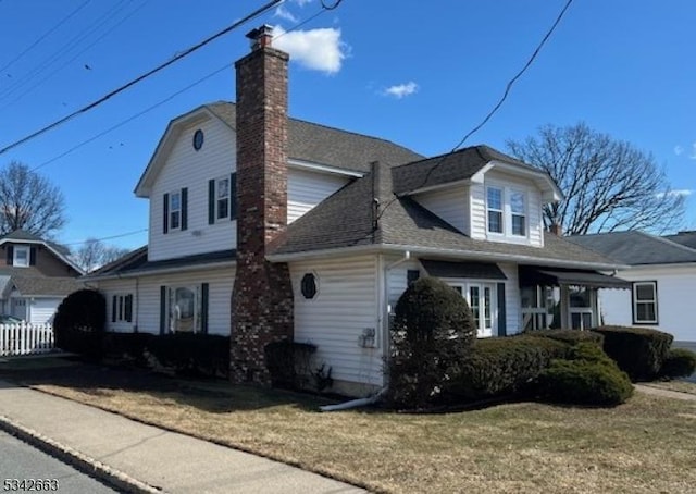 view of property exterior featuring a shingled roof, a lawn, a chimney, and fence