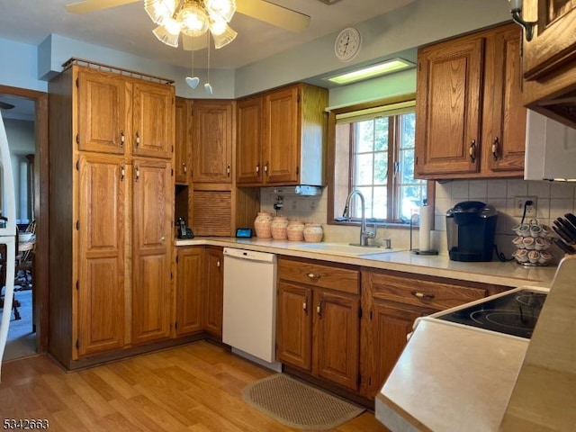 kitchen with light wood finished floors, dishwasher, brown cabinets, light countertops, and a sink