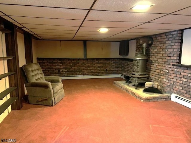 finished below grade area with brick wall, baseboard heating, carpet flooring, and a paneled ceiling