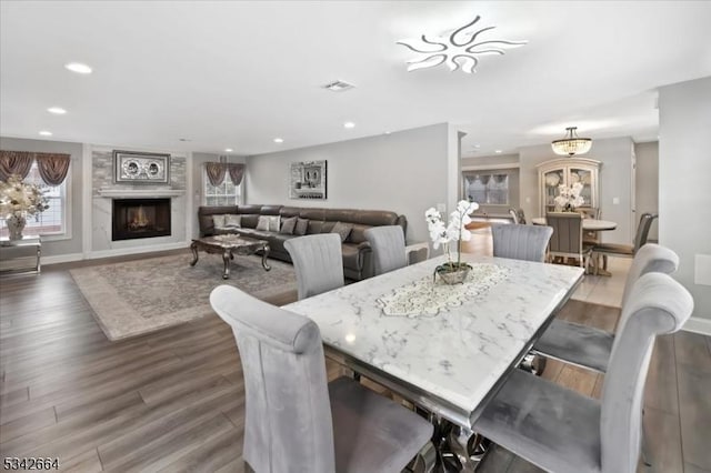 dining space with a lit fireplace, baseboards, dark wood-style flooring, and recessed lighting