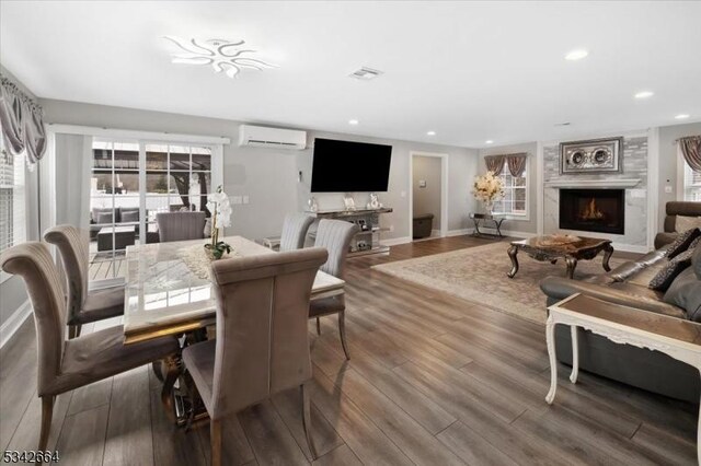 dining area with recessed lighting, a lit fireplace, an AC wall unit, and wood finished floors