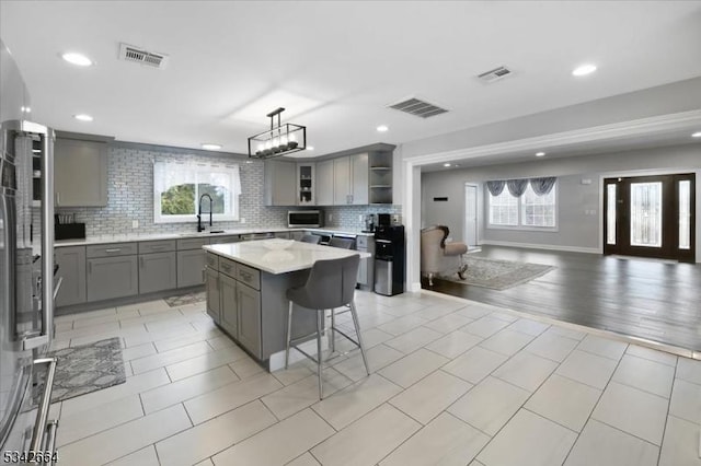 kitchen with open shelves, visible vents, gray cabinets, and open floor plan