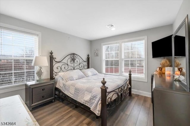 bedroom with visible vents, baseboards, and wood finished floors