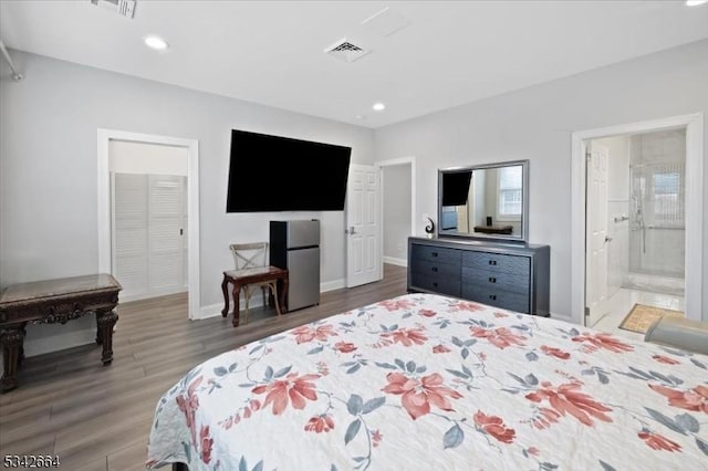 bedroom with recessed lighting, visible vents, freestanding refrigerator, wood finished floors, and baseboards