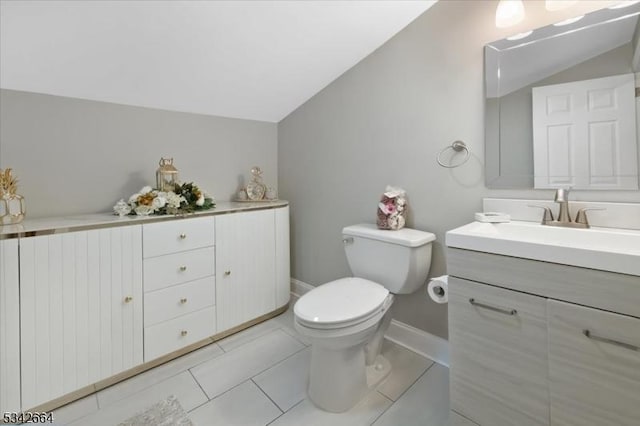 half bathroom with toilet, vanity, baseboards, vaulted ceiling, and tile patterned floors