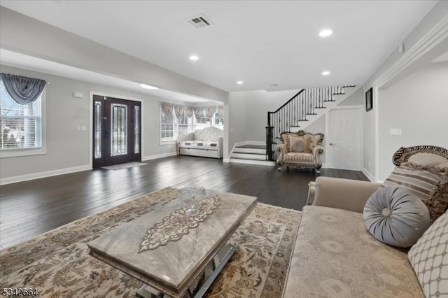 living room featuring baseboards, stairs, visible vents, and wood finished floors