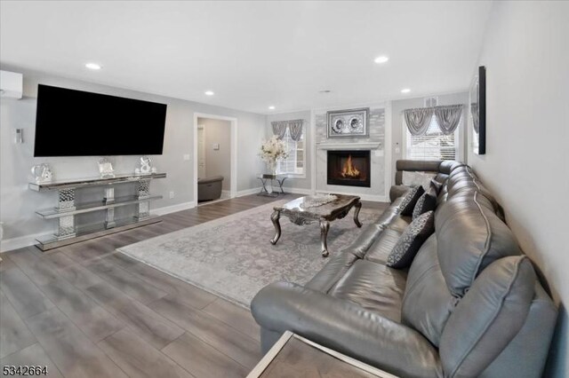 living room with baseboards, a lit fireplace, wood finished floors, and recessed lighting