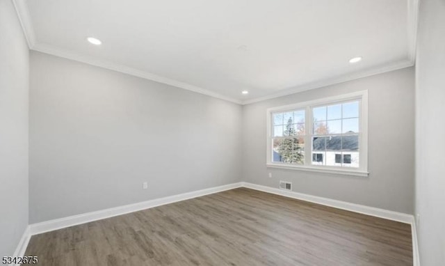 unfurnished room with visible vents, baseboards, wood finished floors, and crown molding