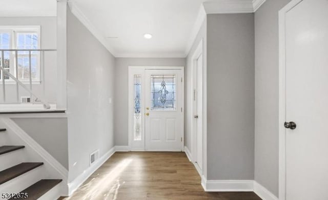 foyer entrance featuring stairs, crown molding, wood finished floors, and baseboards