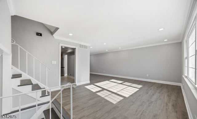 interior space featuring visible vents, crown molding, baseboards, stairway, and wood finished floors