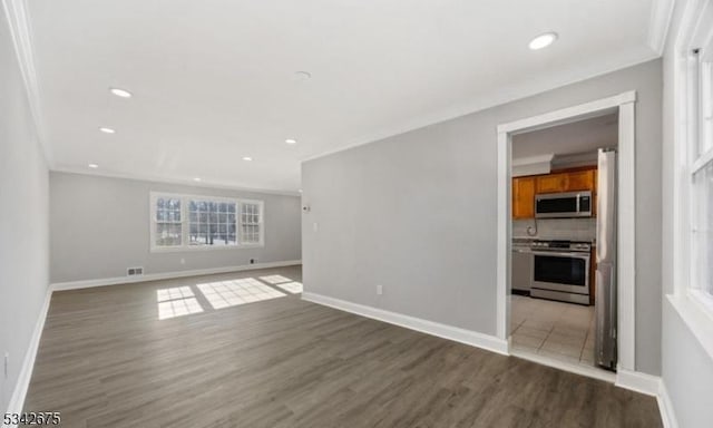 spare room with wood finished floors, baseboards, and ornamental molding