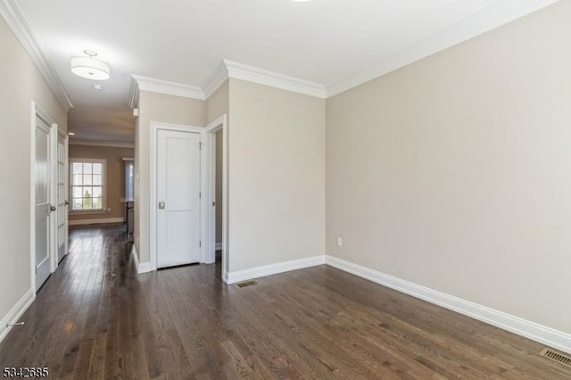 unfurnished room with dark wood finished floors, crown molding, visible vents, and baseboards