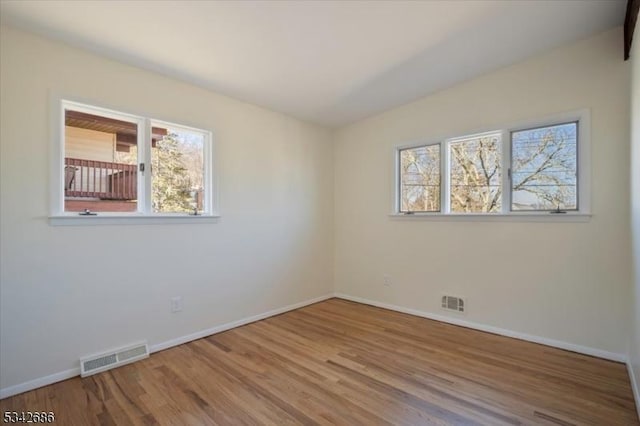 unfurnished room with visible vents, baseboards, and wood finished floors