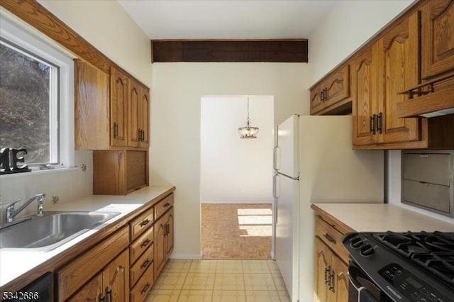 kitchen featuring black gas stove, light floors, dishwashing machine, brown cabinetry, and a sink