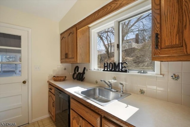 kitchen with brown cabinets, a sink, backsplash, black dishwasher, and light countertops