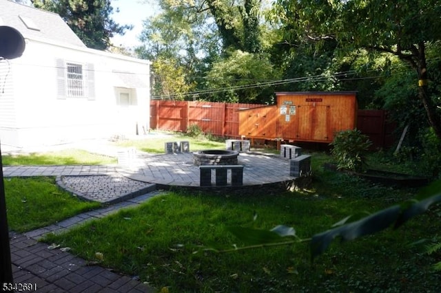 view of yard with fence, a fire pit, an outdoor structure, and a patio