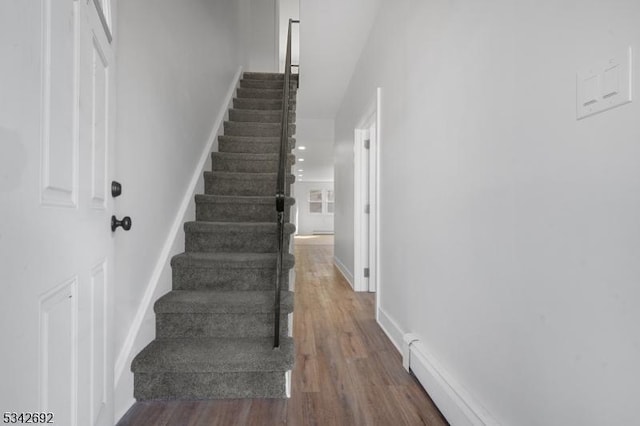 stairway with baseboards, baseboard heating, and wood finished floors