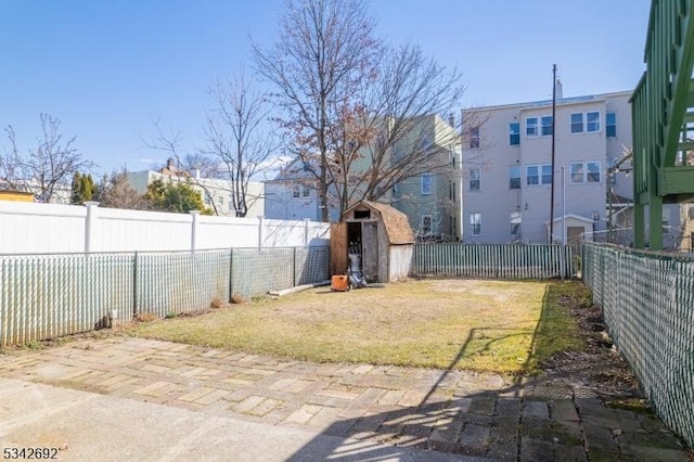 view of yard with an outdoor structure, a fenced backyard, and a shed