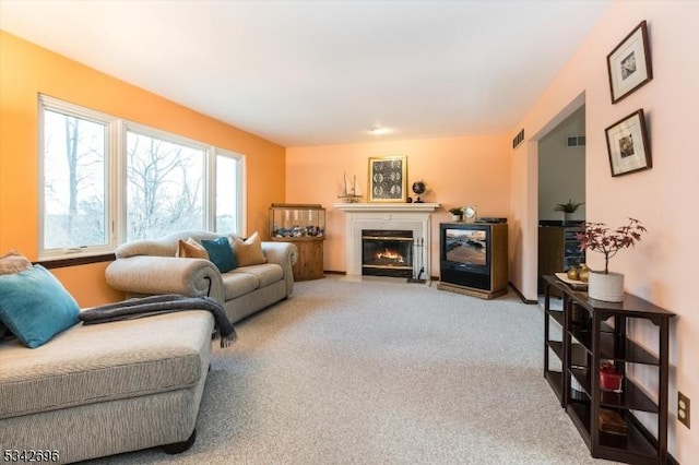 carpeted living room featuring a fireplace with flush hearth and visible vents