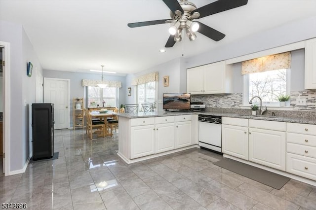 kitchen featuring dishwasher, a peninsula, plenty of natural light, and a sink