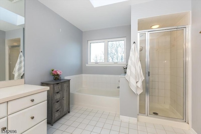 full bath with a skylight, a stall shower, tile patterned floors, a garden tub, and vanity