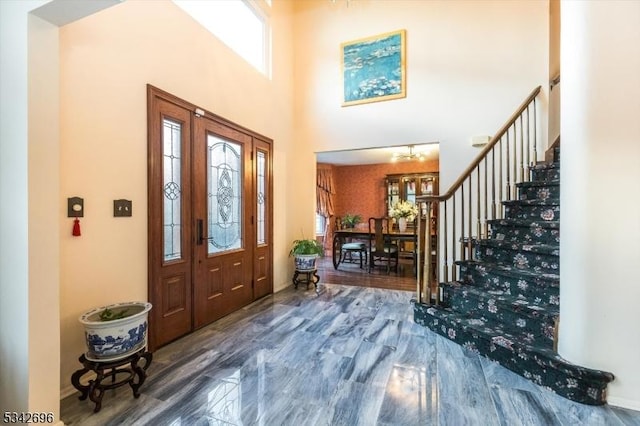 foyer with stairway, a towering ceiling, and wood finished floors