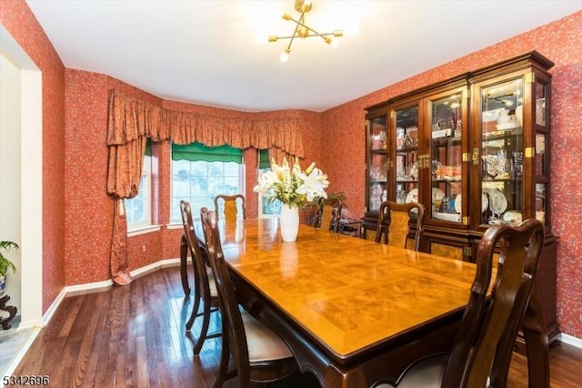 dining space featuring wallpapered walls, baseboards, dark wood-style floors, and a notable chandelier