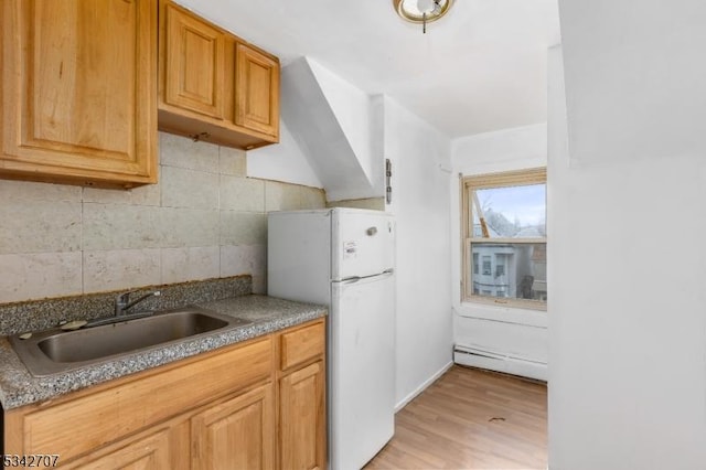 kitchen with freestanding refrigerator, a sink, light wood-style floors, tasteful backsplash, and baseboard heating