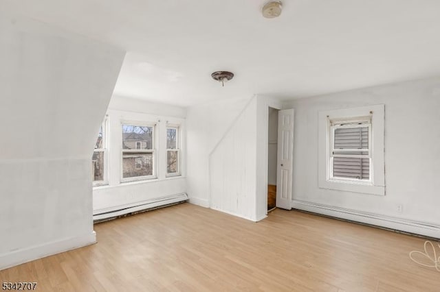 additional living space with baseboard heating, baseboards, and wood finished floors