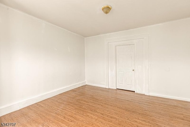 unfurnished room with baseboards and light wood-style floors