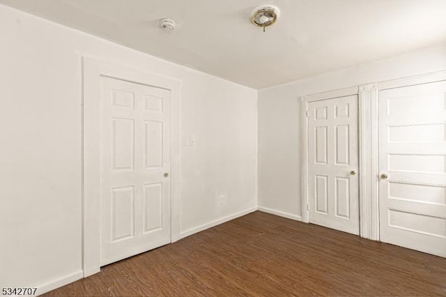 unfurnished bedroom featuring baseboards and dark wood-style flooring